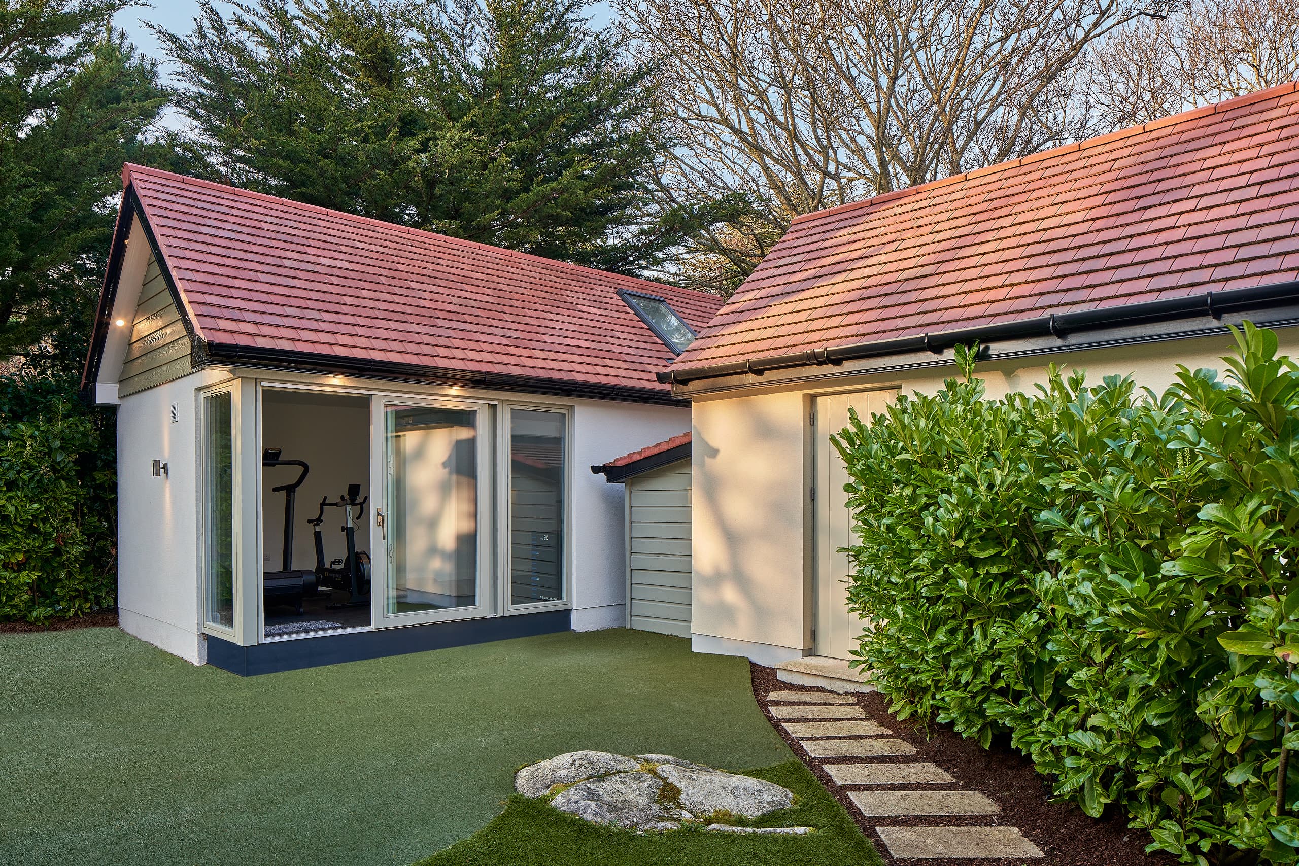 The garden gym studio beside the house, its glazing opening onto the lawn