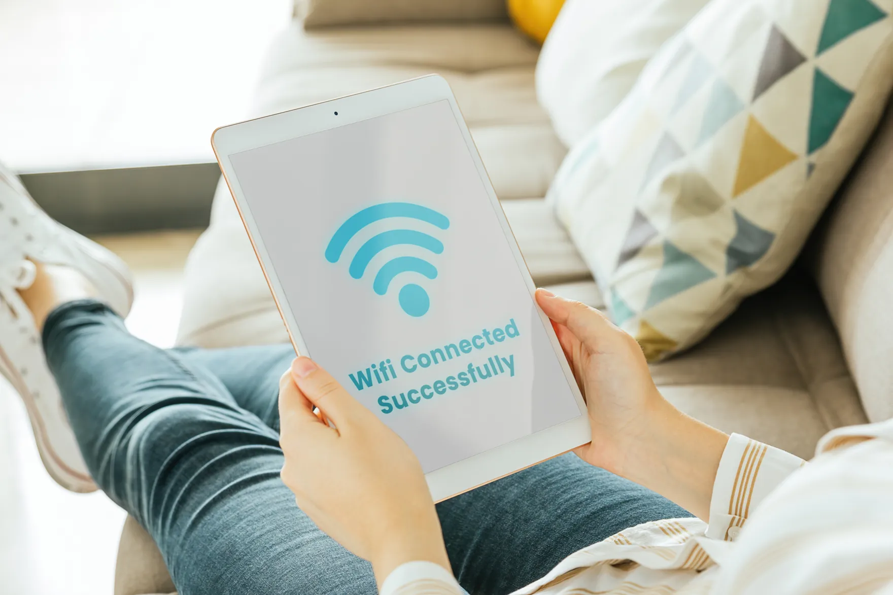 A person on a sofa holding a tablet that reads Wifi Connected Successfully
