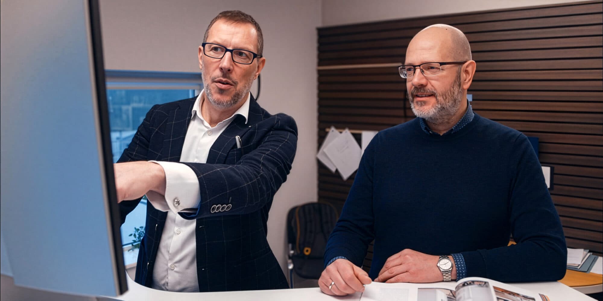 Two members of the Shomera design team reviewing a project on a large monitor in the office