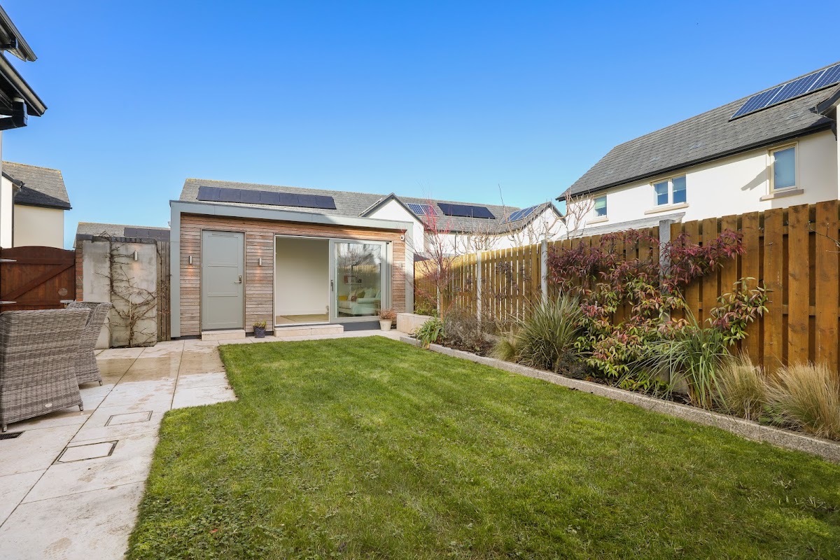 The finished rear garden by day, lawn running up to the studio at the boundary