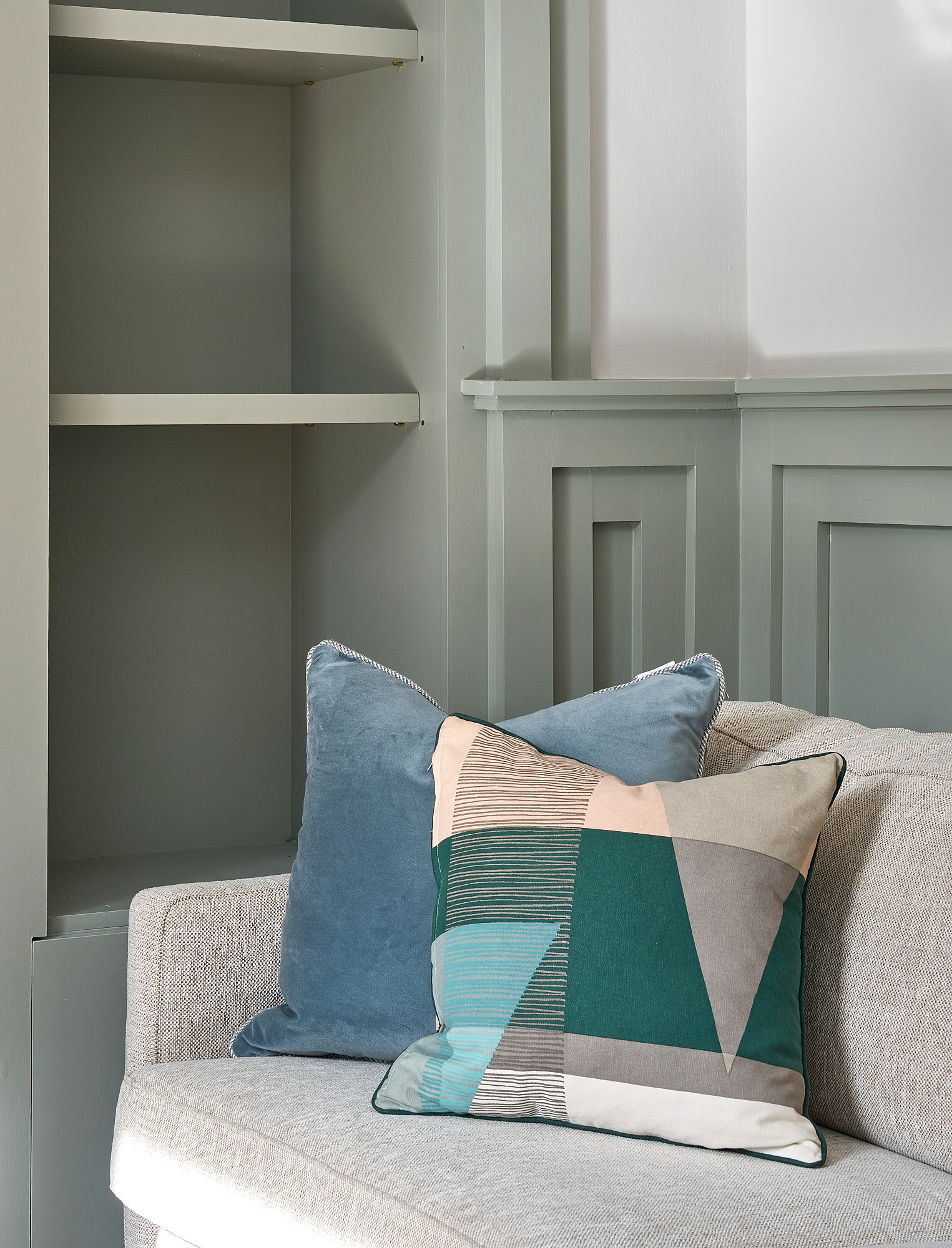 Built-in alcove shelving beside the sofa, painted to match the sage-green panelling