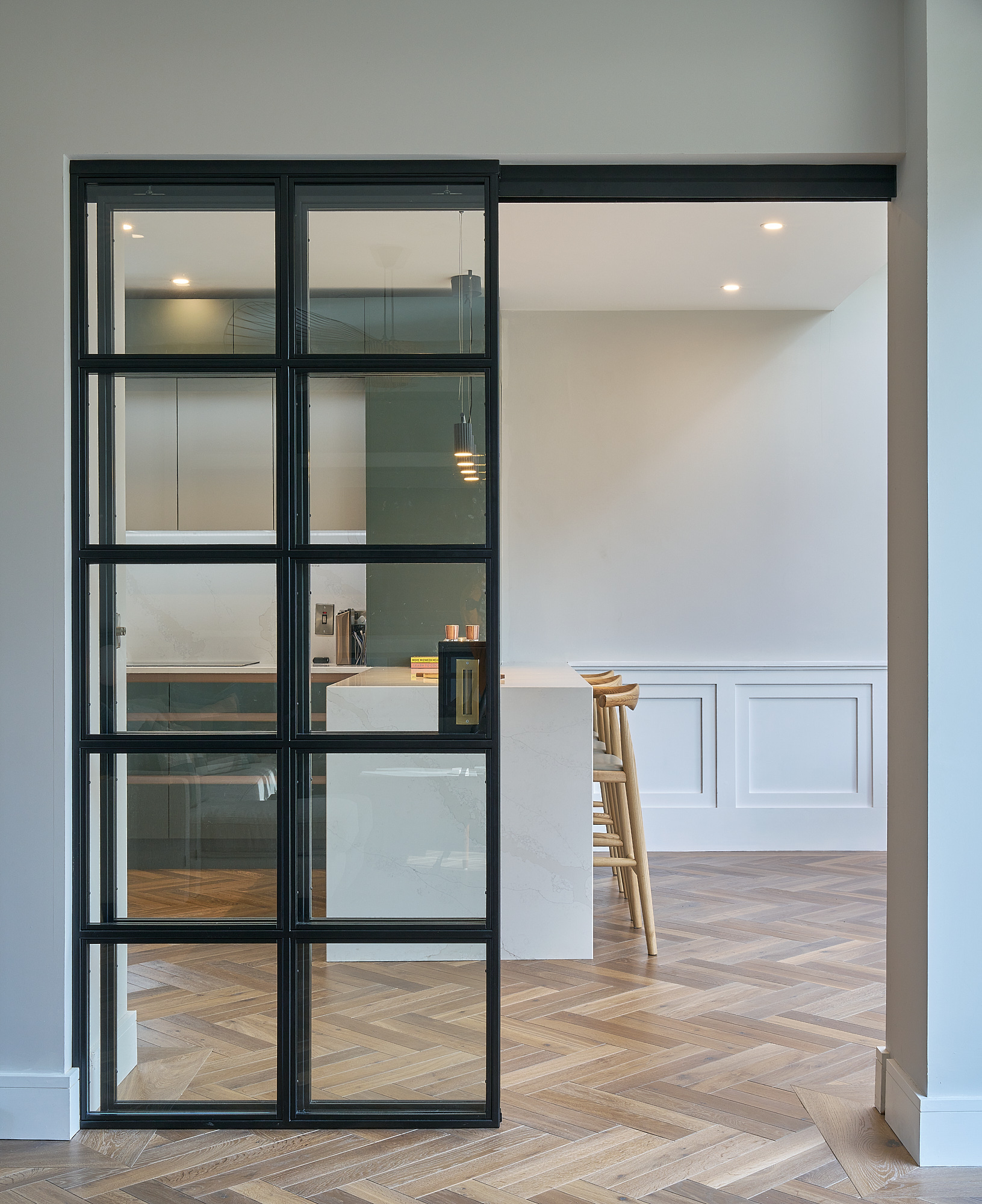 A Crittall-style black glazed sliding door opening from the hallway into the kitchen
