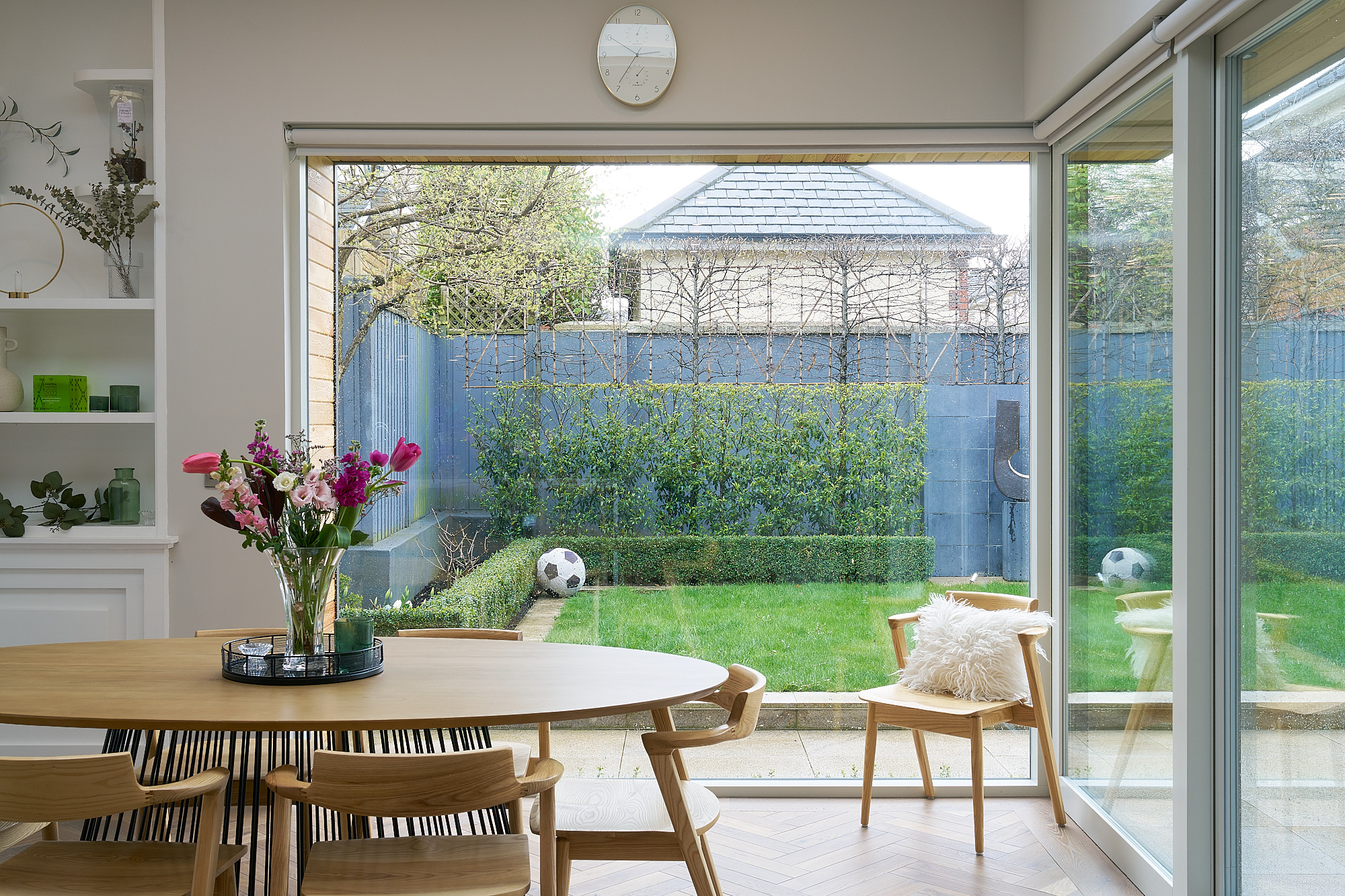 The dining area, a round table set in front of full-height glazing onto the lawn