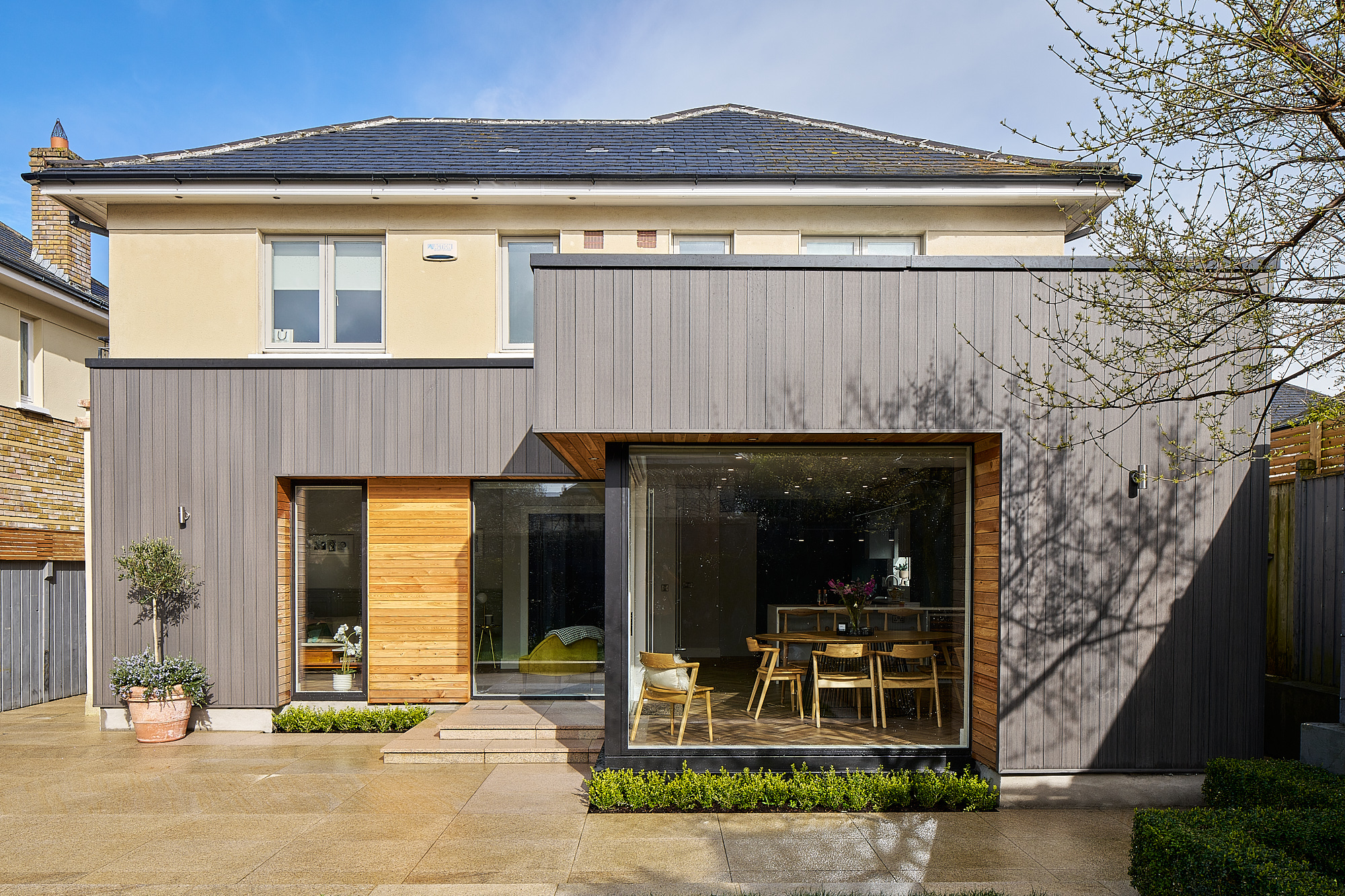 The rear extension by day, its cedar and dark-clad elevation opening onto the patio