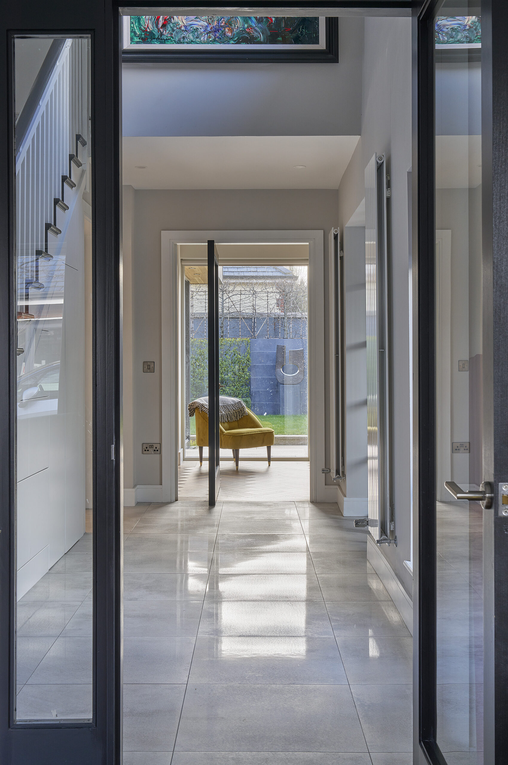 The hallway looking through open doors to the garden beyond, light falling across the polished floor
