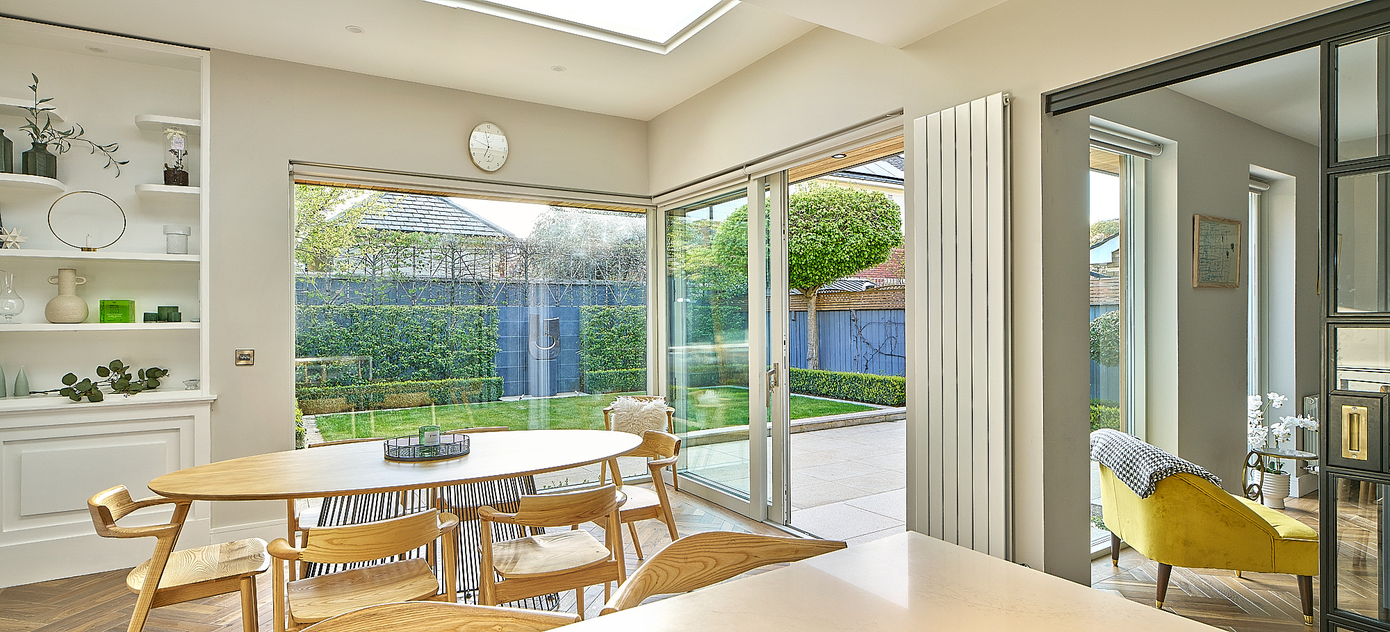 A wide view of the open-plan dining and kitchen space, the garden visible through the glazing