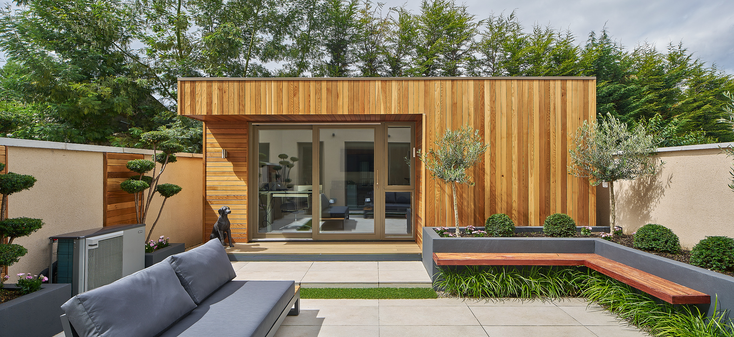 A wide view of the studio and terrace, framed by planting and the boundary wall