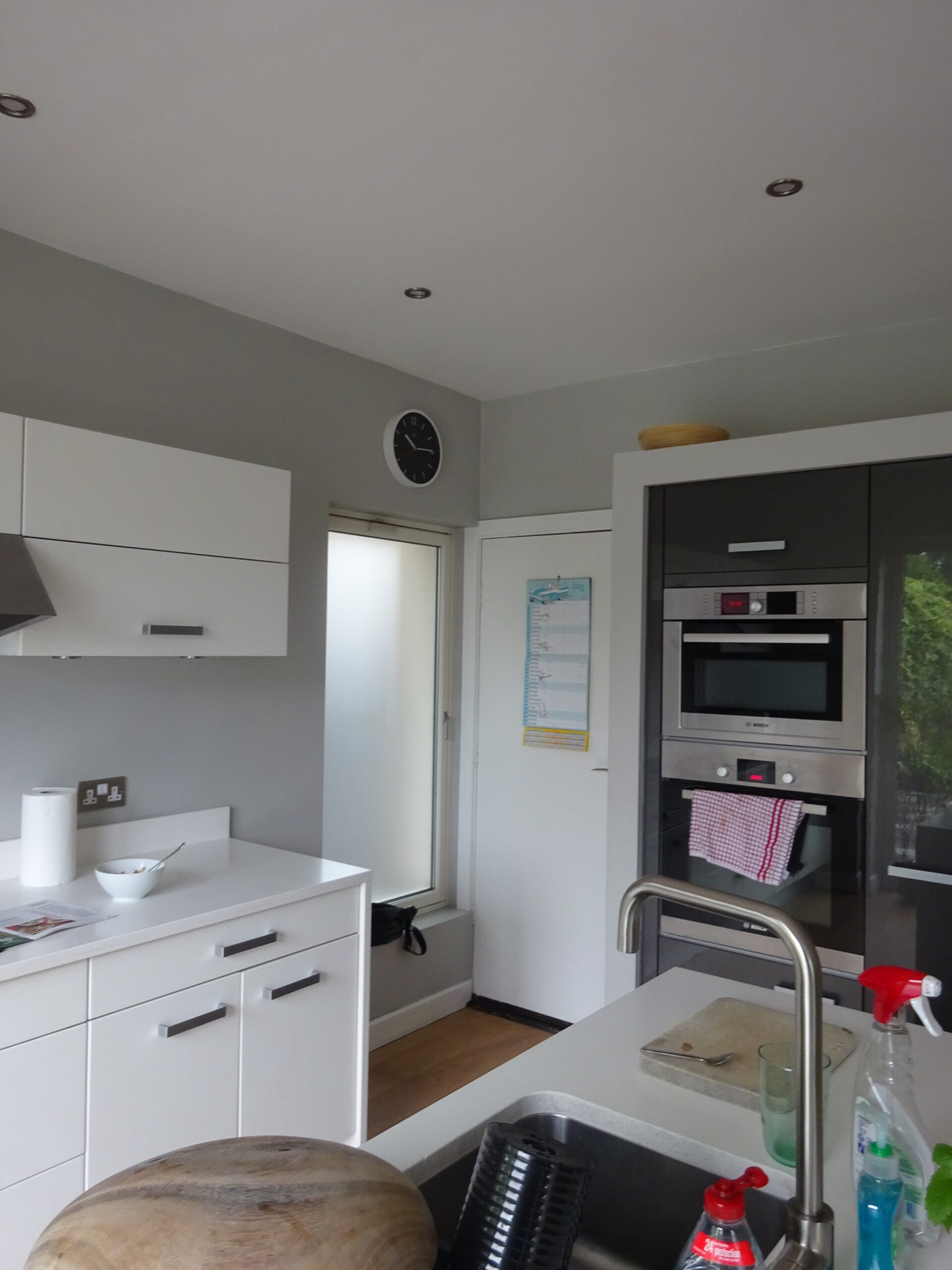 The original kitchen before the works, with white units and a wall-mounted oven stack