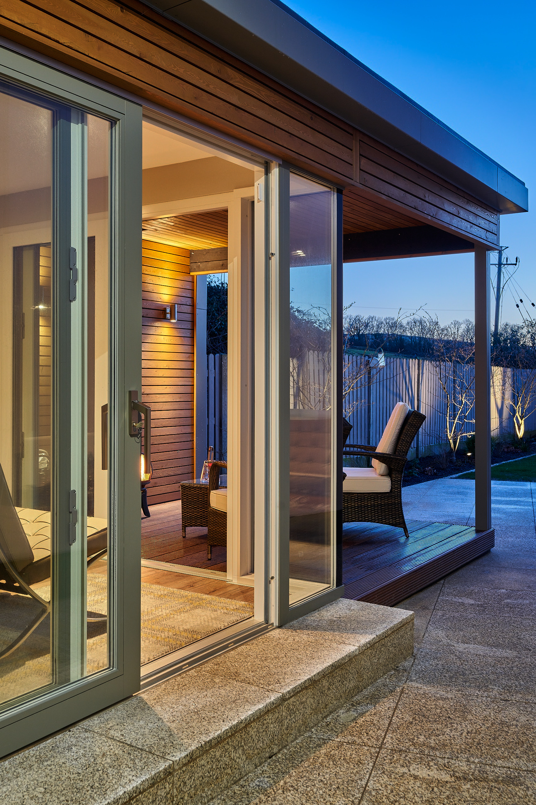 The studio at dusk with its sliding doors open, warm light spilling onto the deck