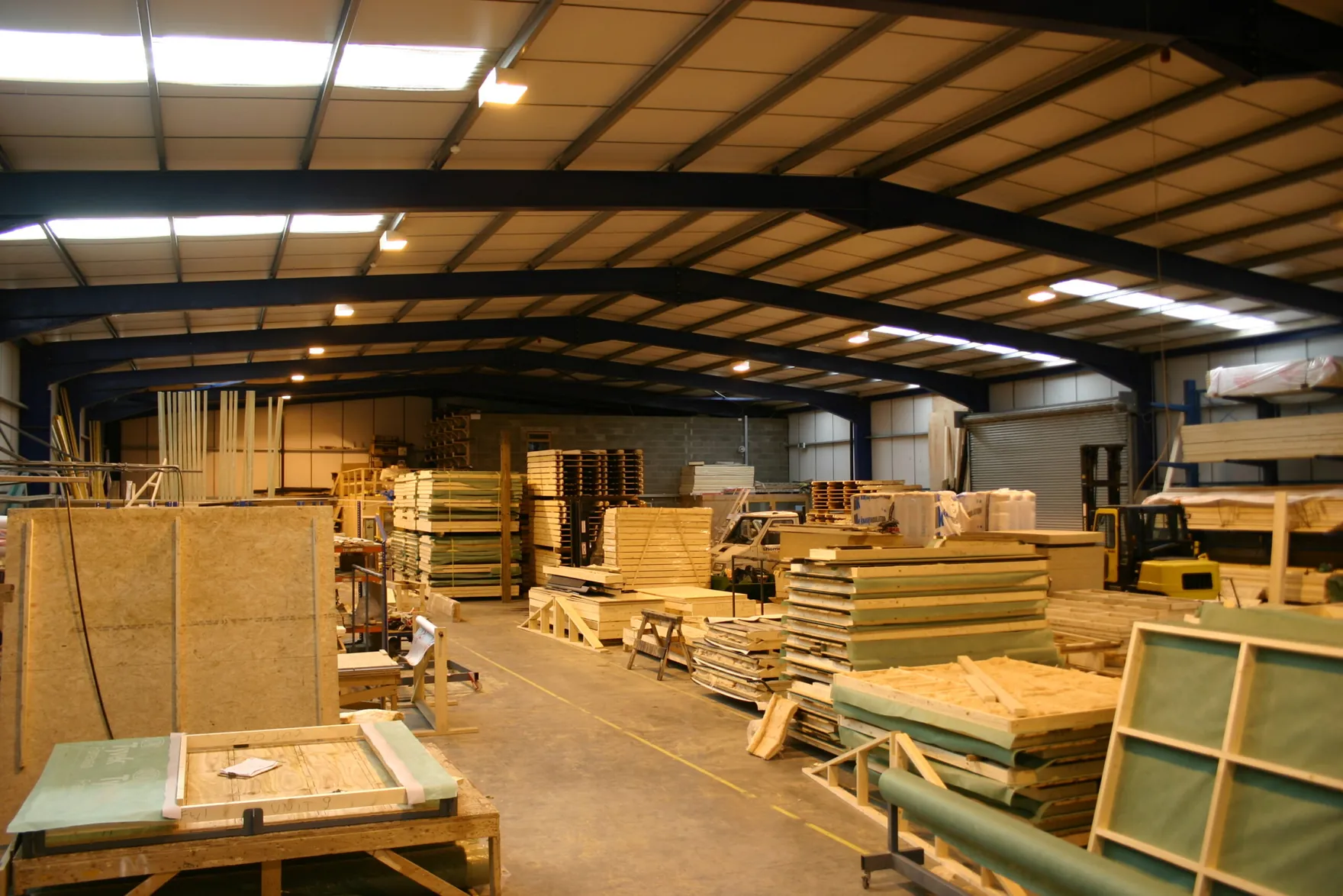 The inside of a workshop with stacks of timber frame panels