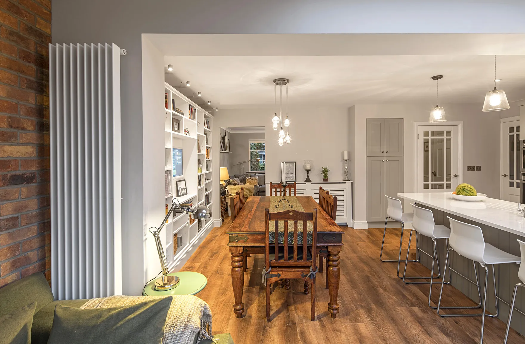 An open-plan dining and kitchen area with a long wooden table, built-in bookshelves and a breakfast bar