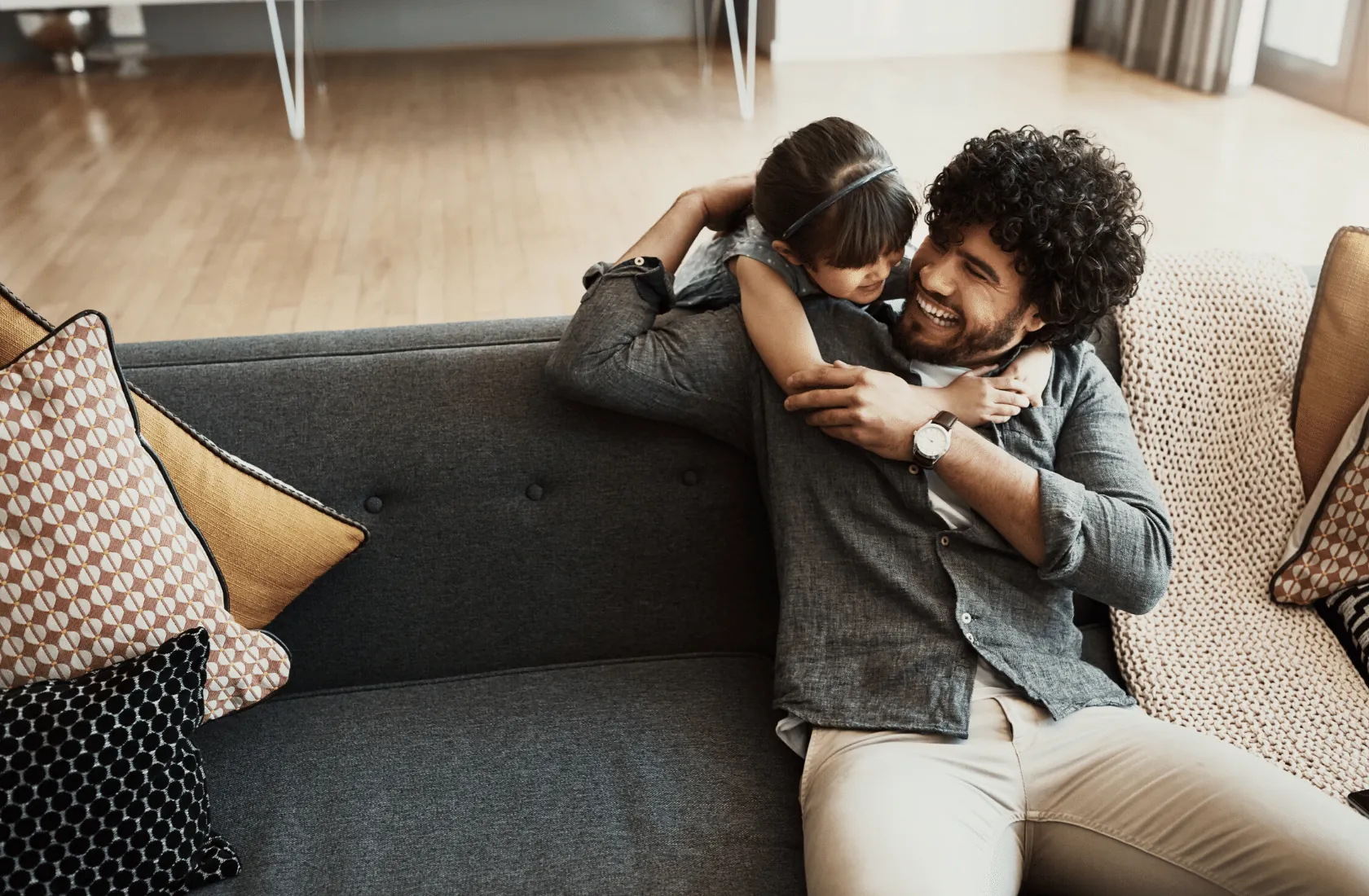 A man and a child hugging on a sofa