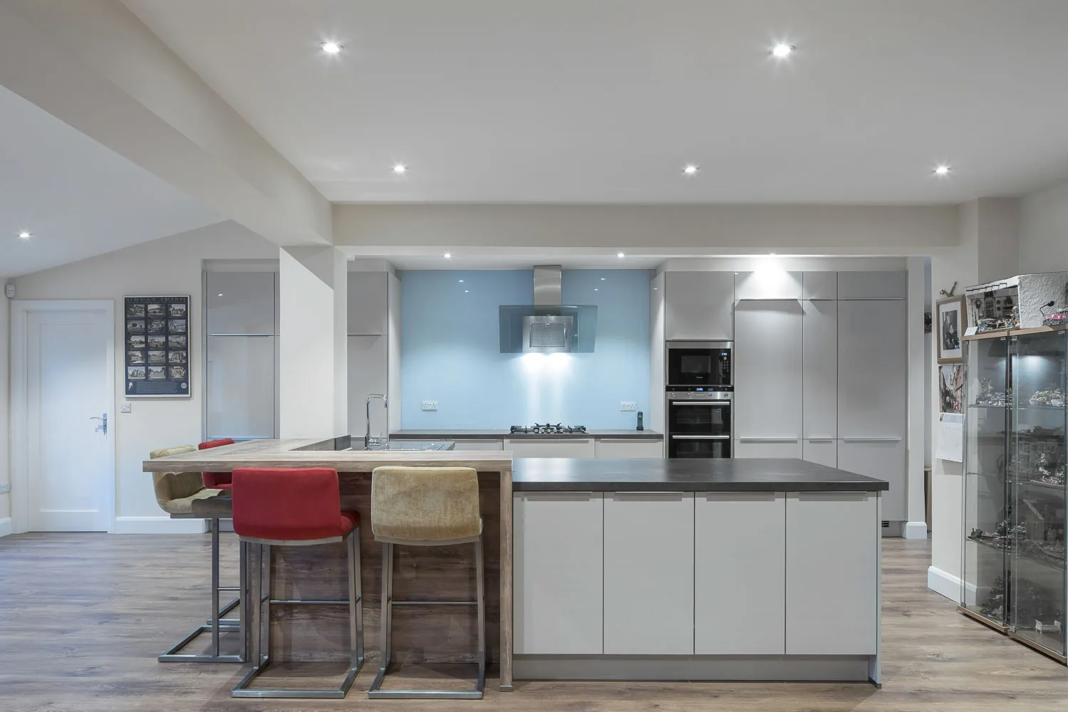 A kitchen with a large island, bar stools and grey handleless units